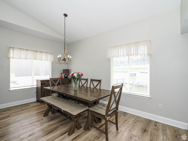 dining area featuring vaulted ceiling, a chandelier, light wood-style floors, and baseboards