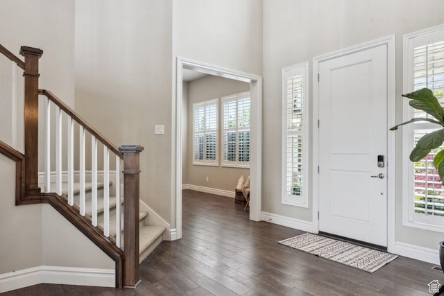 foyer entrance featuring plenty of natural light, stairway, wood finished floors, and a towering ceiling