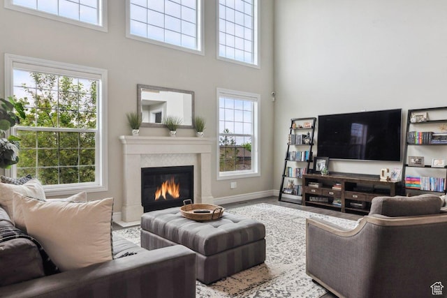 living room with a high ceiling, a fireplace, healthy amount of natural light, and baseboards