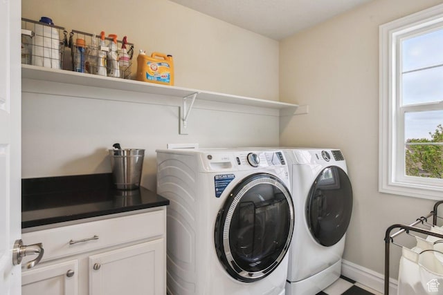 clothes washing area featuring washer and dryer, cabinet space, and baseboards
