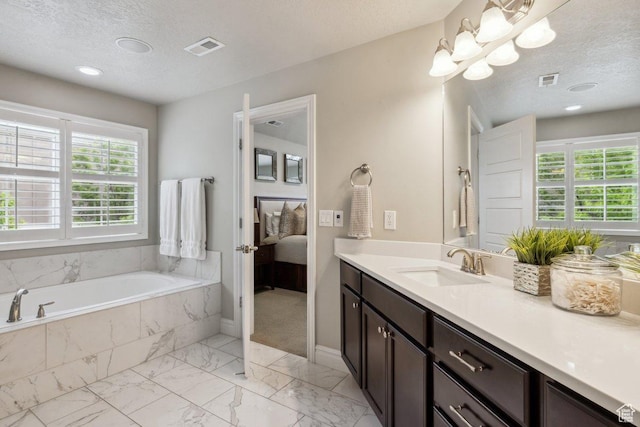 bathroom featuring plenty of natural light, vanity, marble look tiles, a garden tub, and a textured ceiling