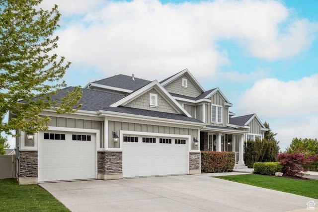 craftsman house with board and batten siding, driveway, a garage, roof with shingles, and stone siding