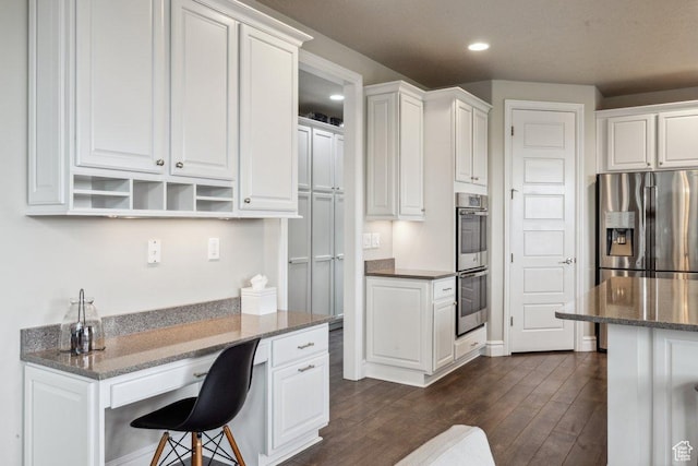 kitchen with stainless steel appliances, dark wood-style floors, white cabinets, recessed lighting, and a breakfast bar