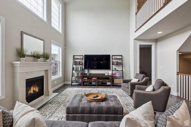 living room with a towering ceiling, wood finished floors, baseboards, and a fireplace with flush hearth