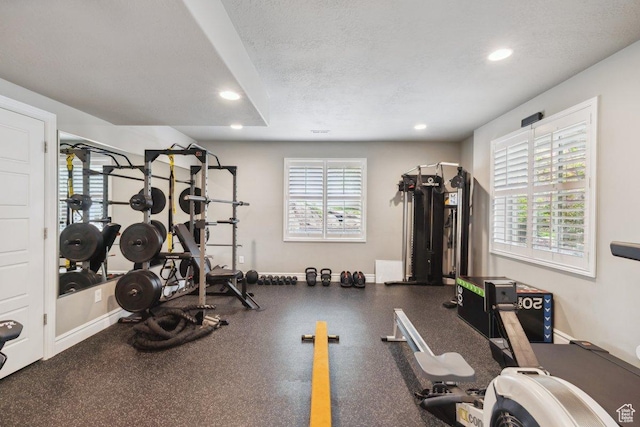 exercise area featuring recessed lighting, baseboards, and a textured ceiling
