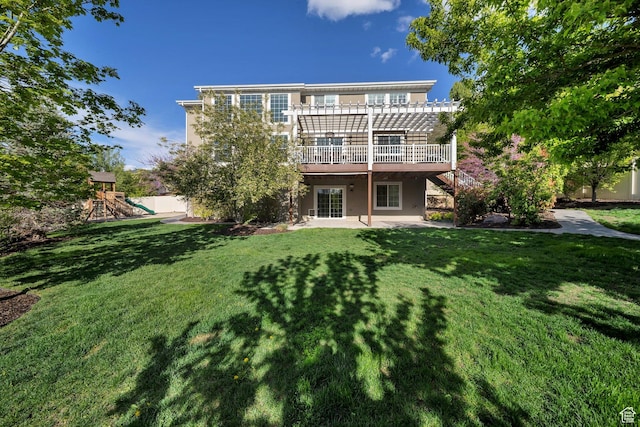 rear view of house with a pergola, a yard, a patio, and a playground