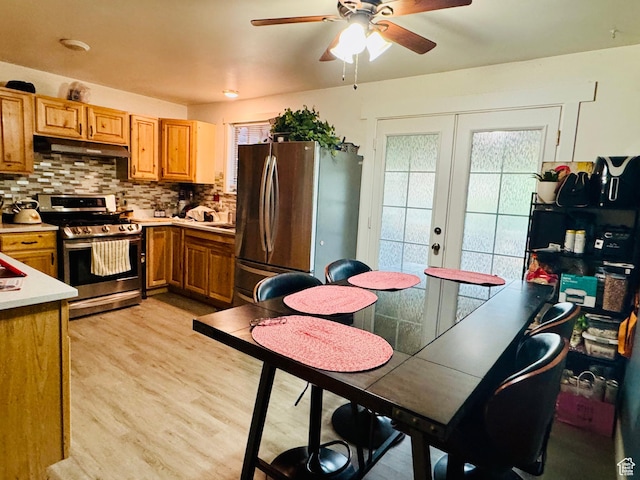 kitchen featuring appliances with stainless steel finishes, under cabinet range hood, light wood-type flooring, tasteful backsplash, and ceiling fan