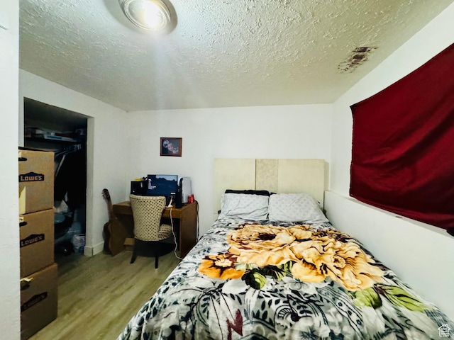 bedroom with wood finished floors and a textured ceiling