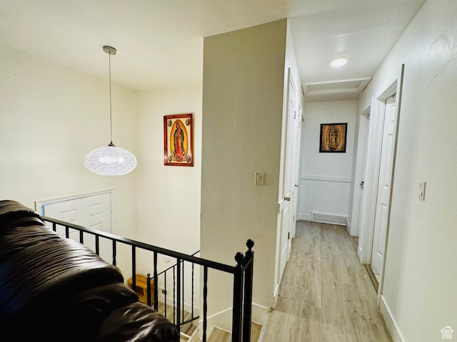 hallway with an upstairs landing, light wood-type flooring, and baseboards