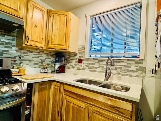 kitchen featuring stainless steel gas range oven, a sink, light countertops, tasteful backsplash, and exhaust hood