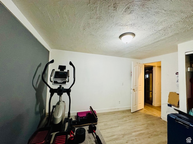workout room with a textured ceiling, wood finished floors, and baseboards