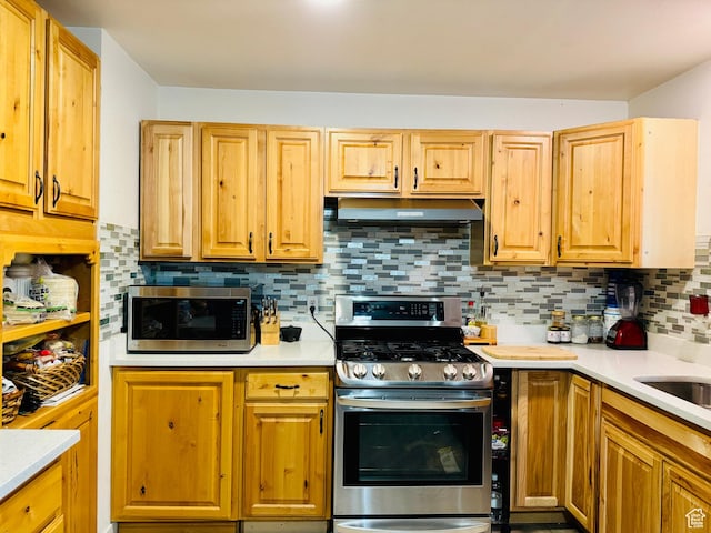 kitchen with stainless steel appliances, under cabinet range hood, light countertops, and decorative backsplash