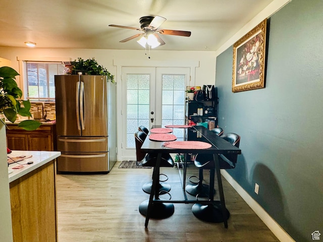 dining area featuring a ceiling fan, french doors, light wood-type flooring, and baseboards
