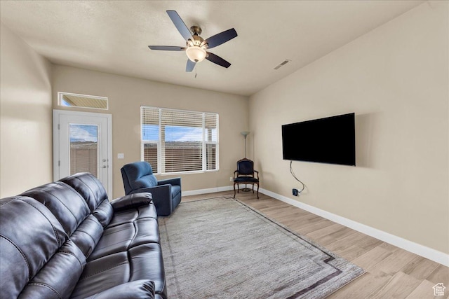 living room with wood finished floors, a ceiling fan, and baseboards