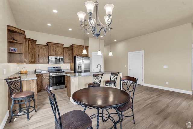 dining room featuring light wood finished floors, baseboards, a chandelier, and recessed lighting