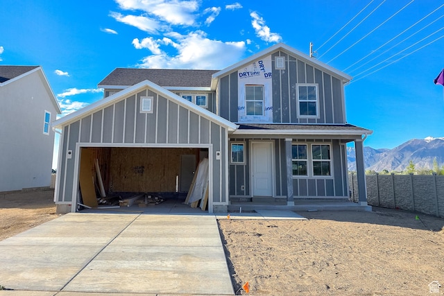 view of front of home with driveway, a garage, board and batten siding, fence, and a mountain view