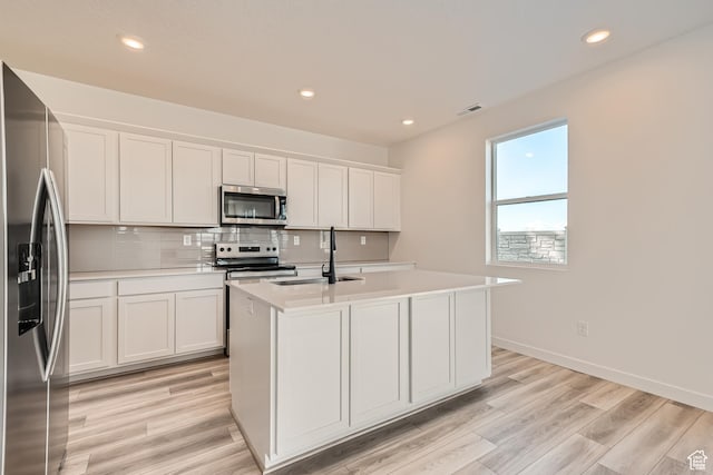 kitchen featuring stainless steel appliances, a sink, light countertops, an island with sink, and recessed lighting