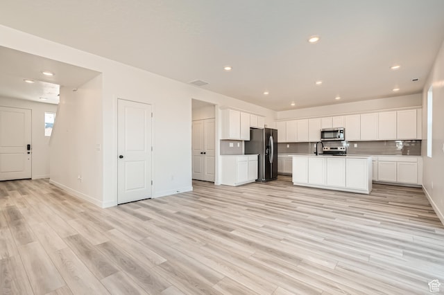 kitchen featuring appliances with stainless steel finishes, light wood-style flooring, white cabinets, open floor plan, and recessed lighting