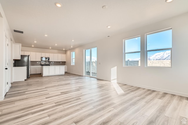 unfurnished living room featuring recessed lighting, light wood-style floors, and baseboards