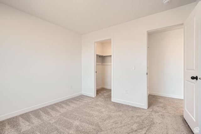 unfurnished bedroom featuring carpet floors, baseboards, a spacious closet, and a closet
