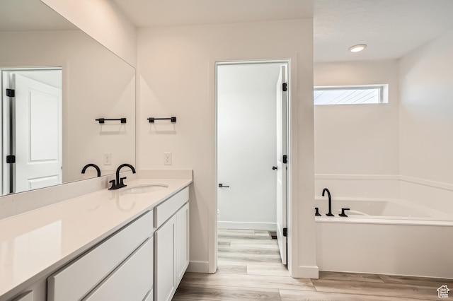 bathroom featuring vanity, a garden tub, wood finished floors, and baseboards