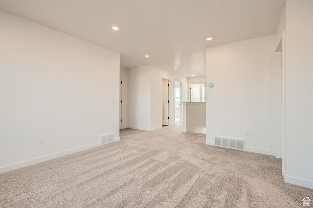 spare room featuring recessed lighting, light colored carpet, and baseboards