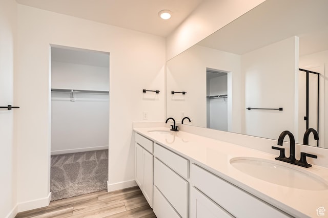 full bathroom with wood finished floors, double vanity, a spacious closet, recessed lighting, and an enclosed shower