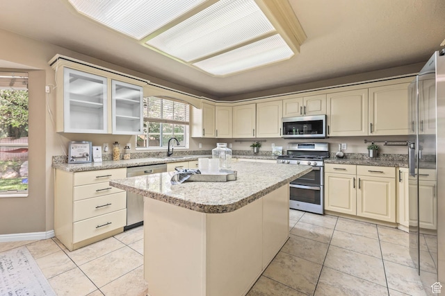 8017 S Showcase Ln, Sandy, UT 84094 - kitchen with stainless steel appliances, a center island, cream cabinetry, and light tile patterned floors