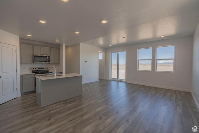 kitchen featuring appliances with stainless steel finishes, gray cabinetry, baseboards, light countertops, and recessed lighting