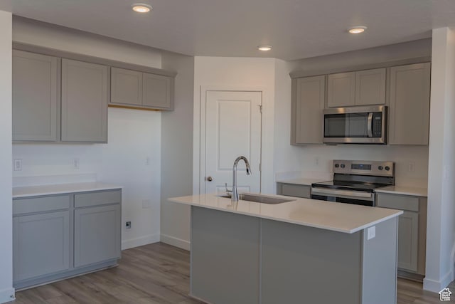 kitchen featuring stainless steel appliances, a sink, gray cabinets, and recessed lighting