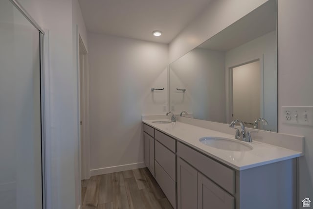 full bath with wood finished floors, double vanity, and baseboards