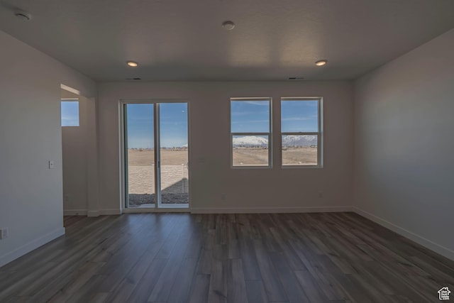 empty room featuring dark wood finished floors, baseboards, and recessed lighting