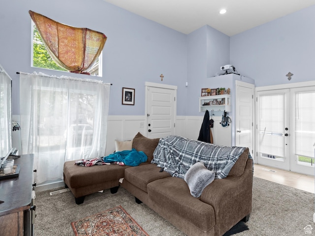 living area with wainscoting, healthy amount of natural light, and french doors