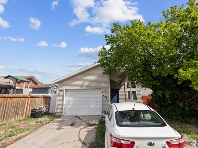 view of front of house with concrete driveway, a garage, and fence