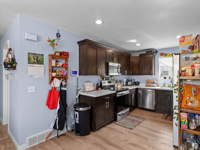 kitchen with stainless steel appliances, light wood finished floors, light countertops, dark brown cabinetry, and baseboards