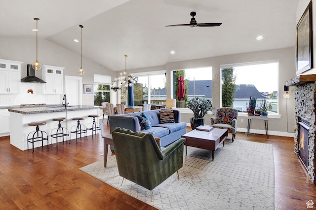 living area featuring ceiling fan, lofted ceiling, wood finished floors, a chandelier, and recessed lighting
