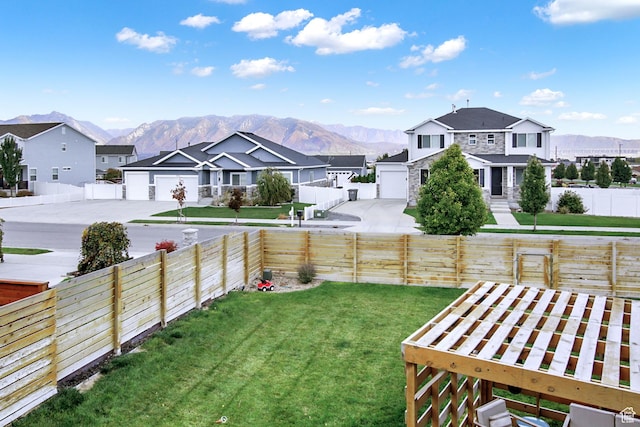 view of yard featuring a residential view, a mountain view, and concrete driveway