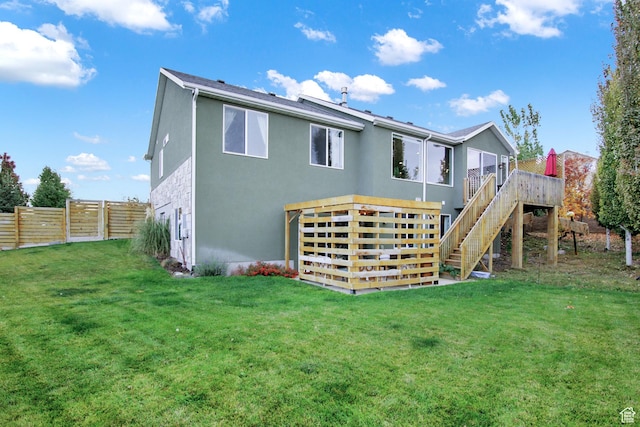 rear view of property featuring stucco siding, stairs, and a deck