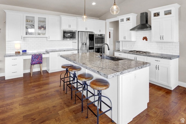 kitchen with wall chimney exhaust hood, appliances with stainless steel finishes, a sink, tasteful backsplash, and recessed lighting