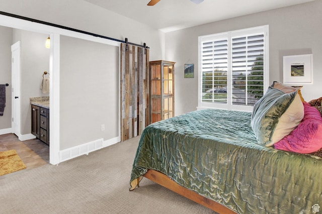 carpeted bedroom with a barn door, ceiling fan, and baseboards