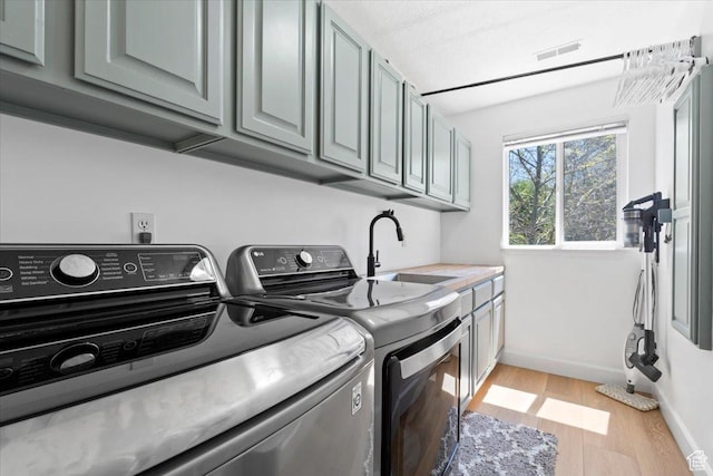 washroom featuring cabinet space, separate washer and dryer, light wood-type flooring, and baseboards