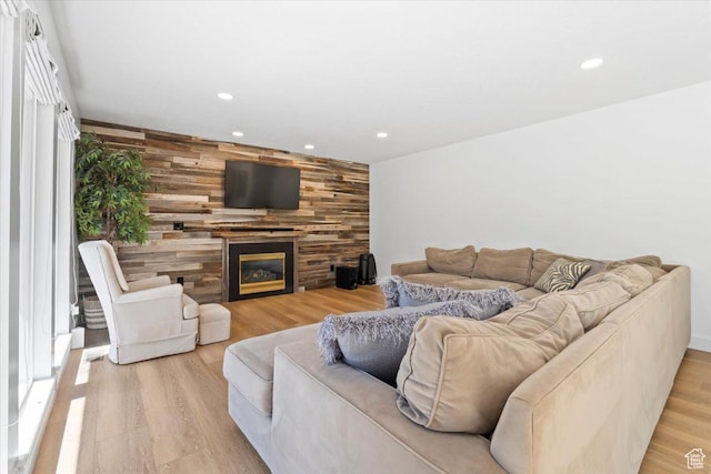 living area with recessed lighting, light wood-type flooring, a large fireplace, and wooden walls