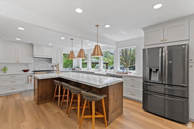 kitchen with appliances with stainless steel finishes, backsplash, plenty of natural light, light stone countertops, and recessed lighting
