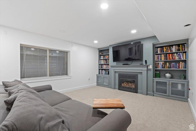 carpeted living room featuring baseboards, recessed lighting, a glass covered fireplace, and built in features