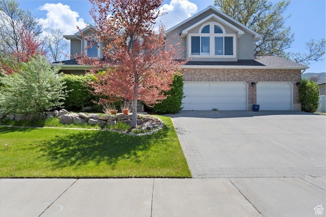 view of front facade featuring driveway, a front yard, brick siding, a garage, and stucco siding