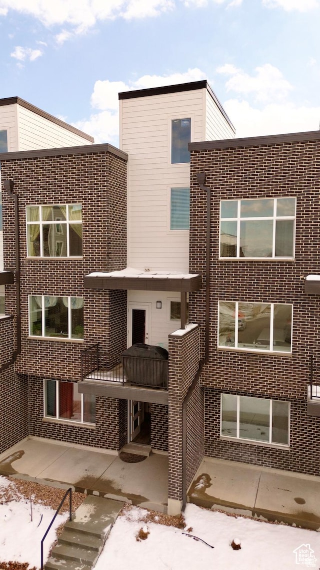 back of house featuring brick siding and a patio