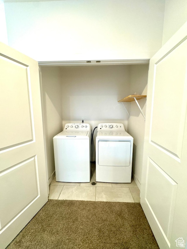 clothes washing area featuring washer and dryer, light colored carpet, light tile patterned floors, and baseboards