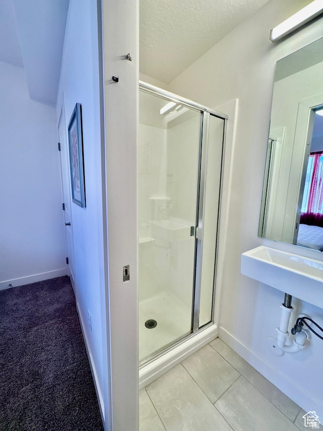 bathroom with a shower stall, baseboards, tile patterned floors, and a textured ceiling
