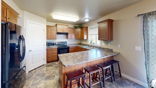 90 W Cedar Ln, Franklin, ID 83237 - kitchen with black appliances, a peninsula, a sink, under cabinet range hood, and a kitchen breakfast bar