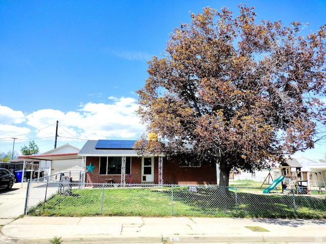view of front facade with brick siding, a playground, solar panels, a carport, and concrete driveway